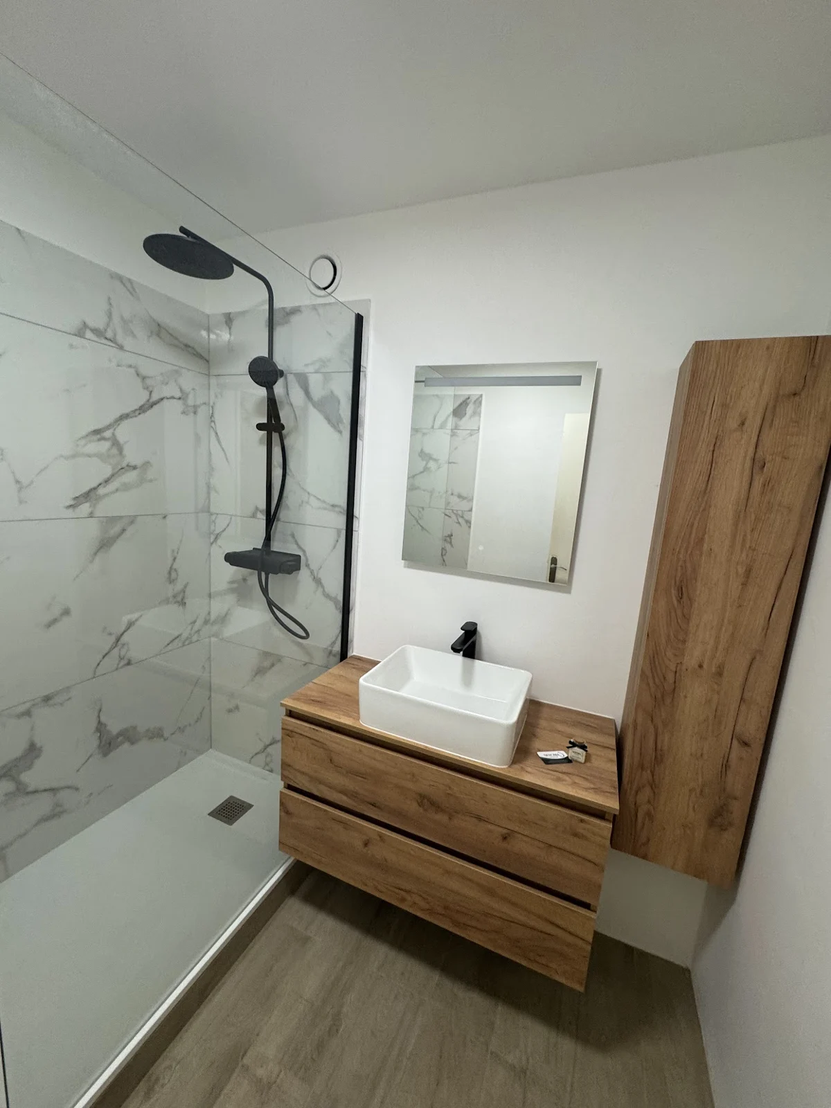 Salle de bain avec douche, meuble en bois et effet marbre