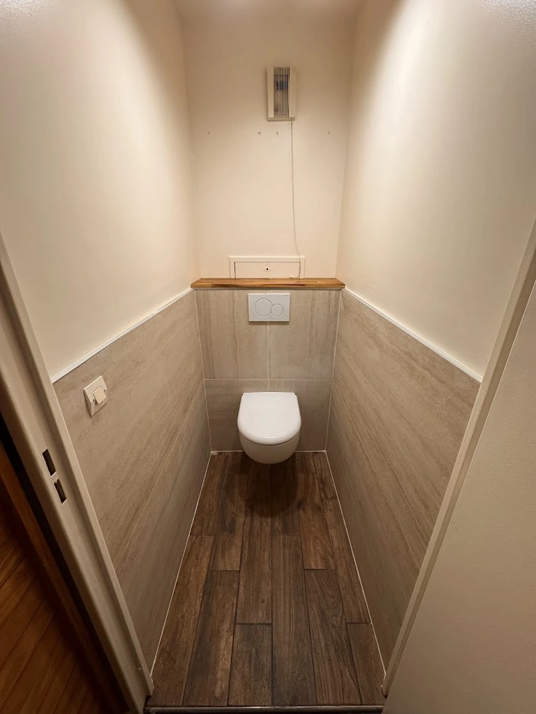 WC suspendu blanc, carrelage mural beige et sol effet bois