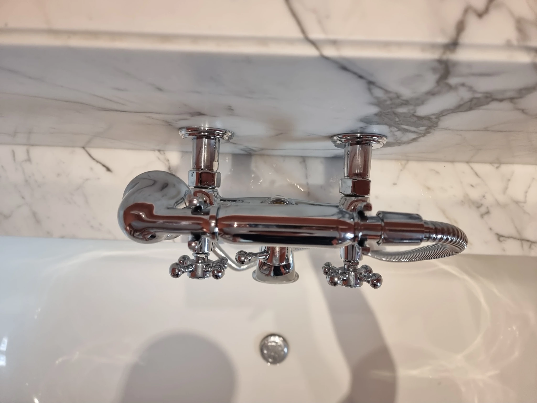 Robinet de baignoire chromé à poignées croisillons sur carrelage effet marbre